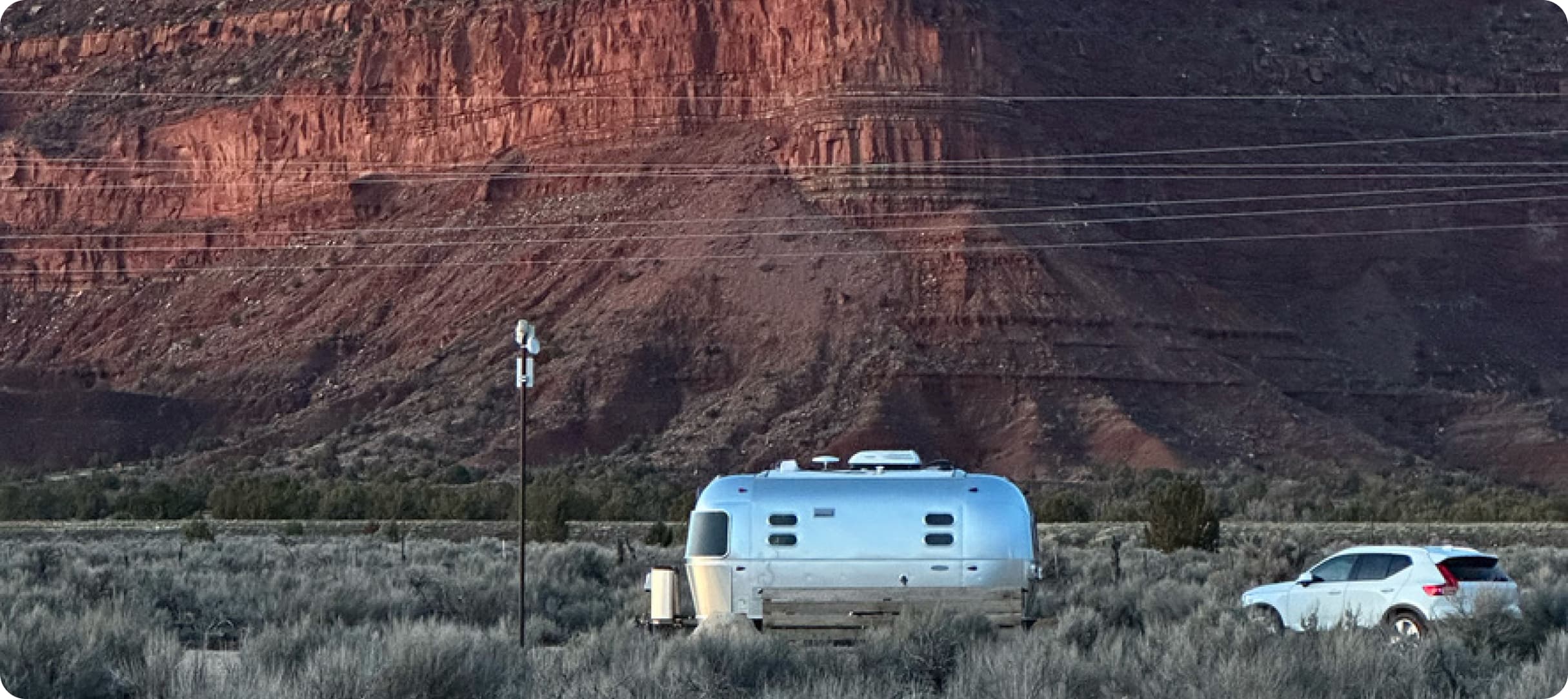 Airstream trailer in front of dramatic red rock cliffs